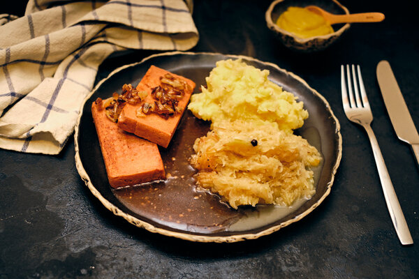 Pflanzlicher Leberkäse mit karamellisierten Zwiebeln, Sauerkraut, Kartoffelbrei, Bratensoße und Senf
